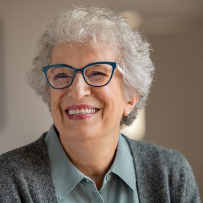 Happy retired senior woman wearing spectacles and relaxing at home. Carefree old woman wearing eyeglasses at home and smiling. Portrait of joyful grandmother with eyewear and toothy smile.